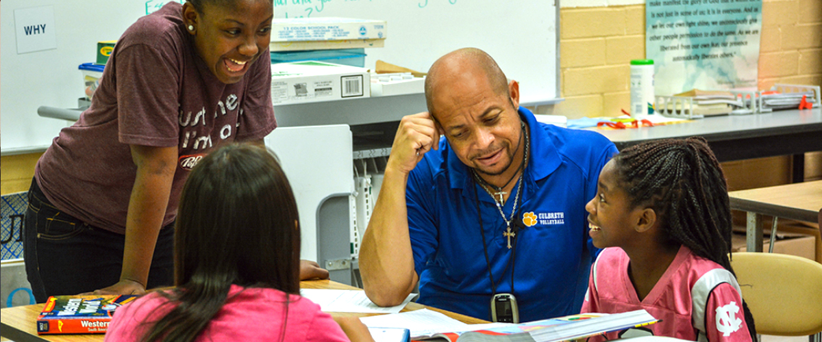 A teacher helping three students with homework after school 